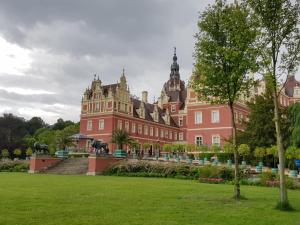 um grande edifício vermelho com um parque verde em frente em Ferienwohnungen Stricker em Bad Muskau