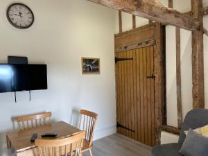 a living room with a table and a wooden door at The Cow Shed 2-Bed Apartment in Bradwell on Sea in Bradwell on Sea