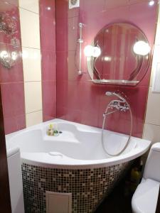 een badkamer met een bad, een wastafel en een spiegel bij Апартаменти в центрі міста in Kamjanets-Podilsky