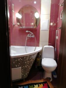 een badkamer met een bad, een toilet en een spiegel bij Апартаменти в центрі міста in Kamjanets-Podilsky