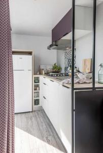een keuken met witte kasten en een zwarte koelkast bij Chênefleur in Tintigny