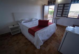 um quarto com uma cama com uma almofada vermelha em Pousada Cachoeira Poço Encantado em Alto Paraíso de Goiás