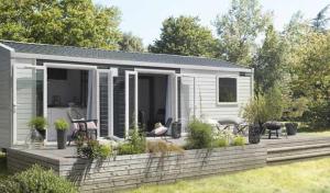 een klein huis met een houten terras in een tuin bij Chênefleur in Tintigny