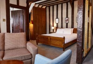 a bedroom with a bed and a couch and a chair at Bull Hotel by Greene King Inns in Long Melford