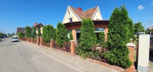 a house with a fence and trees on a street at Šarlotos apartamentai in Klaipėda