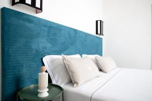a white bed with white pillows and a green table at Villa delle Palme in Santa Marinella