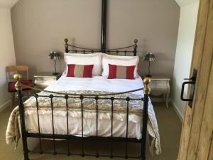 a bedroom with a bed with red and white pillows at Impeccable cottage suitable for Three adults in Tockwith