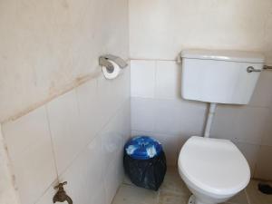 a bathroom with a toilet and a trash can at Captivating 3-Bed House in Moshi Town in Uru
