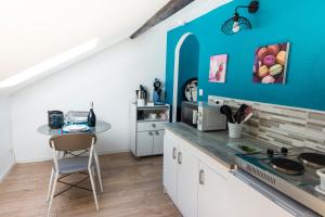 a kitchen with white cabinets and a blue wall at Escale à Épernay in Épernay