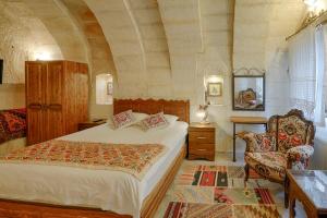 格雷梅的住宿－鬱金香洞穴套房酒店，一间卧室配有一张大床和一把椅子