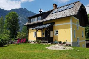 una casa amarilla con sillas rojas en un patio en Ferienhaus Kopriwa, en Bad Goisern