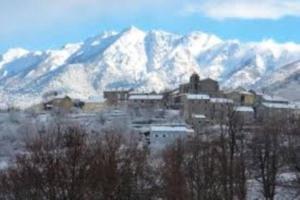 a city with snow covered mountains in the background at chez LULU appartement neuf au coeur de cozzano in Cozzano