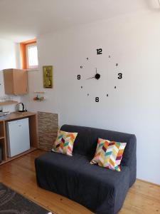 a living room with a couch and a clock on the wall at Peter rooms in Ljubljana