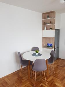 een eetkamer met een witte tafel en stoelen bij S&D Apartman in Lukavica