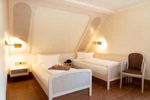 a small room with two beds and a chair at Häuser der Villa Italia in Marktheidenfeld