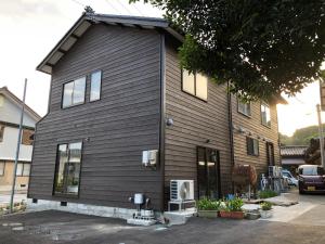 une maison noire avec des fenêtres latérales dans l'établissement 九右衛門ゲストハウス(kuemon guesthouse), à Noroshi