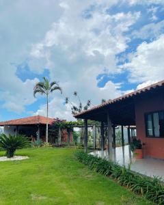 a house with a palm tree in front of a yard at Sítio Nicolau - Maravilhoso sítio nas Montanhas em Domingos Martins! in Domingos Martins