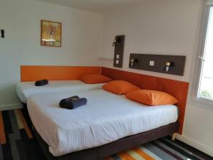 2 camas con almohadas de color naranja en una habitación en Kyriad Direct Saintes en Saintes