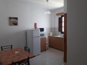 a kitchen with a table and a white refrigerator at PHILIPPOS STUDIOS & APT in Líndos