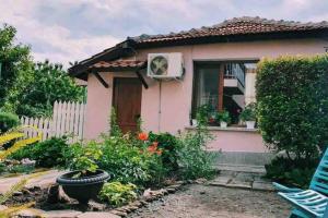 uma pequena casa cor-de-rosa com uma janela e um quintal em Cute Little House with a White Picket Fence em Burgas