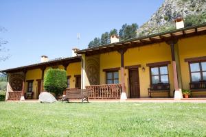Las RozasにあるApartamentos Camin De Pelayoの芝生のベンチ付黄色い家