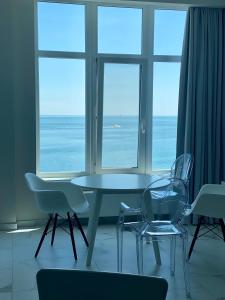 een tafel en stoelen in een kamer met uitzicht op de oceaan bij MAGNIT Apartments у самого моря in Odessa