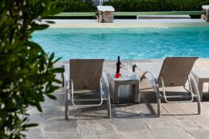 Duas cadeiras e uma mesa com uma garrafa de vinho em Xerolithia em Kamari
