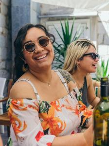 Due donne con gli occhiali da sole in piedi accanto a una bottiglia di vino di Booze & Snooze Social Hostel a Spalato (Split)