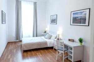 a white bedroom with a bed and a desk and a window at FriendHouse Apartments in Krakow