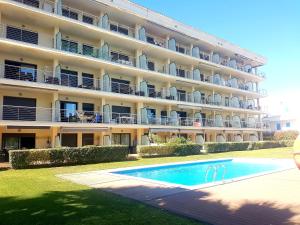 a hotel with a swimming pool in front of a building at Beautiful apartment 75m2 with view at the beach, pool, parking in Roses