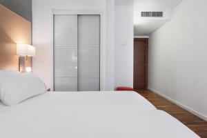 a white bedroom with two beds and a closet at Eurostars Marqués de Vallejo in Logroño