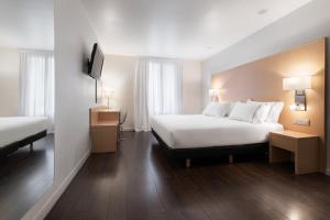 a hotel room with two beds and a television at Eurostars Marqués de Vallejo in Logroño