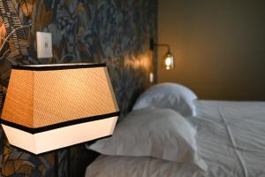 a lamp on the side of a bed with pillows at Hôtel Les Muses in Annecy