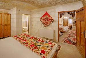 a room with a large bed, a table, and a painting on the at Tulip Cave Suites in Göreme