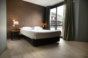 a bedroom with a bed and a large window at Hôtel Les Muses in Annecy