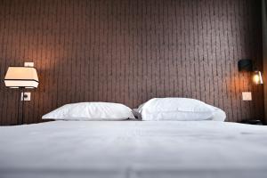 a bedroom with a white bed with two pillows at Hôtel Les Muses in Annecy