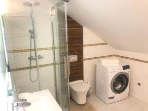 a bathroom with a shower toilet and a washing machine at Apartamenty u Maksa in Reczpol +54 photos