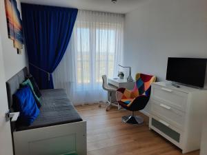 Schlafzimmer mit einem Bett und einem Schreibtisch mit einem TV in der Unterkunft Aqua Apartments Sunset in Reda