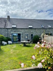 a stone house with a table and chairs in a yard at La Gervaiserie - 300m de la plage in Réville