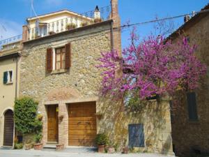 an old stone building with a tree with purple flowers at La Casa di Lucia in Castelmuzio
