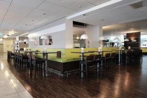 a restaurant with a long bar with stools at Webers - Das Hotel im Ruhrturm in Essen