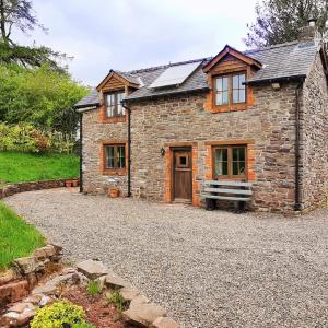 a stone house with a gravel driveway in front of it at Eco Cottage Joe the Buck in Craven Arms