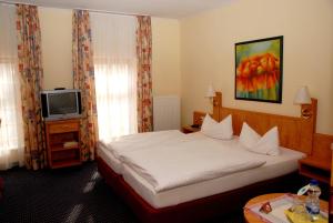 a hotel room with a bed and a tv at Hotel Alte Schule in Luhden