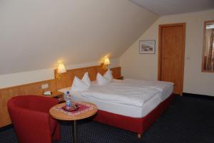 a hotel room with a bed and a red chair at Hotel Alte Schule in Luhden