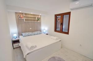 a white bedroom with a bed and a mirror at Nikola Lux apartments in Muo