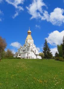 een groot wit gebouw met een gouden dak op een veld bij Babičkin Dom in Medzilaborce