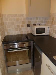 a kitchen with a stove and a microwave at 2 berth ground floor flat Apsley 2 in Great Yarmouth