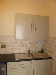 a kitchen with a sink and white cabinets at 2 berth ground floor flat Apsley 2 in Great Yarmouth