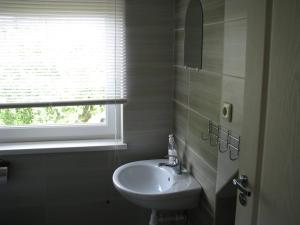 a white bathroom with a sink and a window at Jasmīni in Ventspils