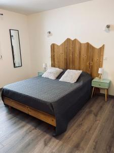 - une chambre avec un grand lit et une tête de lit en bois dans l'établissement Le Gîte de mon grand père, à La Bresse